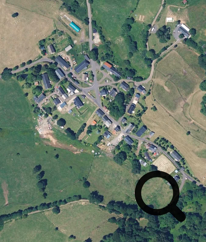 Vue aérienne d'un village avec des routes, des bâtiments et des champs environnants.