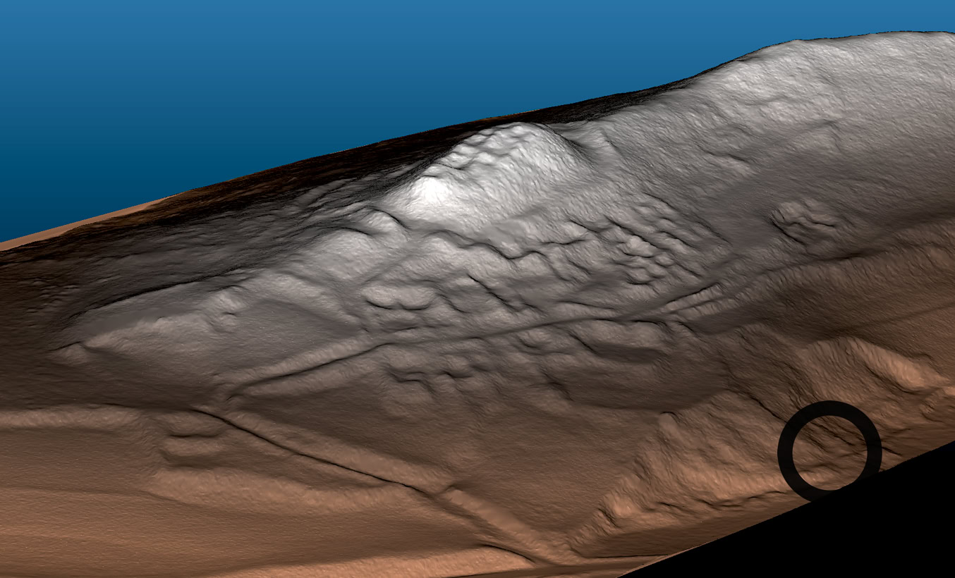 Image en relief d'une surface rocheuse avec des motifs et des textures variés, éclairée par une lumière venant du haut.