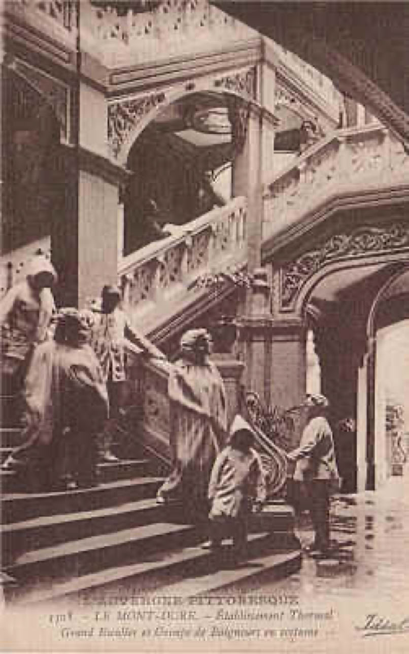 Des personnes montant un grand escalier décoratif à l'intérieur d'un bâtiment.